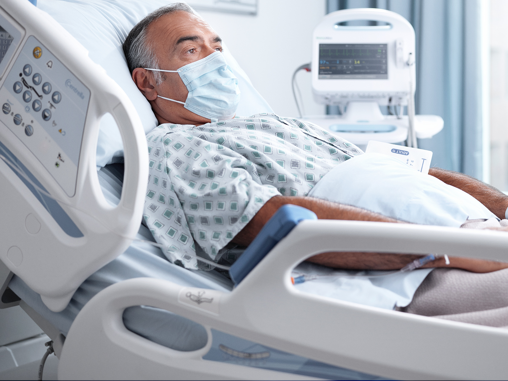 Patient in a hospital bed wearing PPE